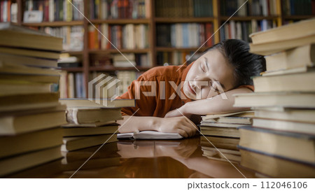 Tired asian student sleeping on stack of book, taking a break from studying 112046106