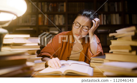 Exhausted medical student falling asleep while working on project at library 112046143