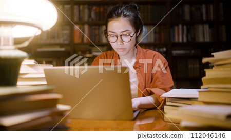Asian female freelancer working late at night at city library, doing research Asian female freelancer working late at night at city library, doing research 112046146