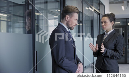 Strict female company boss giving instructions to nervous male employee, office Strict female company boss giving instructions to nervous male employee, office 112046160