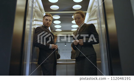 Elevator door opening, embarrassed couple of colleagues exiting, caught flirting Elevator door opening, embarrassed couple of colleagues exiting, caught flirting 112046191