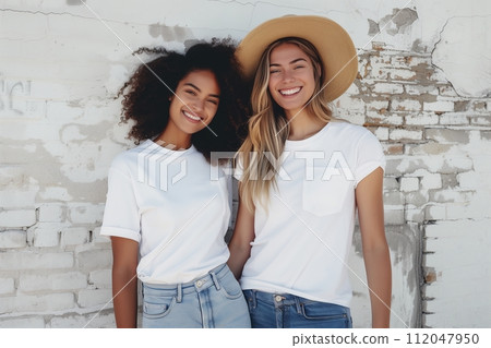 two friends in white t-shirts and jeans, one of them with a hat two friends in white t-shirts and jeans, one of them with a hat 112047950