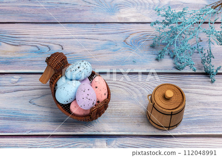 Colorful Easter eggs in a wicker basket on the wooden background Colorful Easter eggs in a wicker basket on the wooden background 112048991