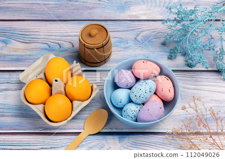 Bowl and a cardboard box with Easter eggs on the wooden background. Bowl and a cardboard box with Easter eggs on the wooden background. 112049026