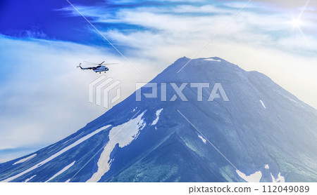 Helicopter flying over Ilyinsky Volcano and Kurile lake on sunlight 112049089