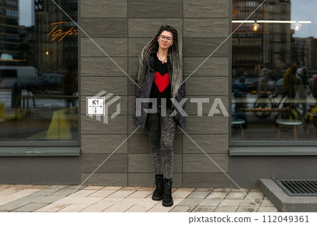 Street fashion concept, young European woman with dreadlocks wearing a dark jacket in an urban 112049361