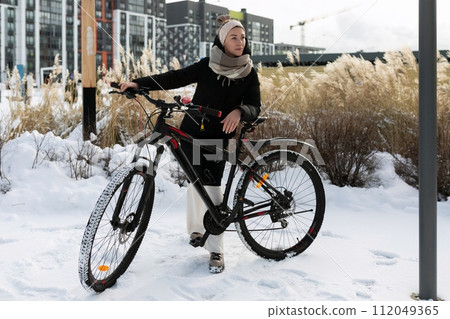 Athletic active young woman riding a bicycle on the street in winter Athletic active young woman riding a bicycle on the street in winter 112049365