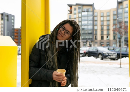 Lifestyle concept, young European woman with informal dreadlocks hairstyle drinks coffee while Lifestyle concept, young European woman with informal dreadlocks hairstyle drinks coffee while 112049671