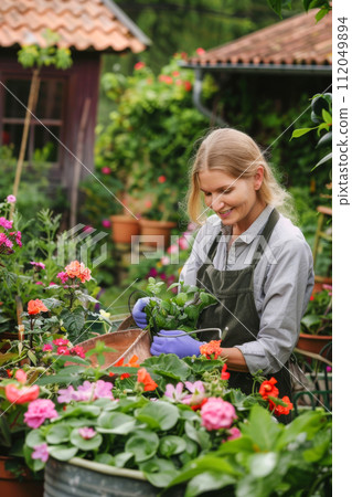 Young woman working  in greenhouse. She selecting garden flowers 112049894