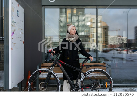 Smiling cute woman with blond dreadlocks rented a bicycle in winter 112050570