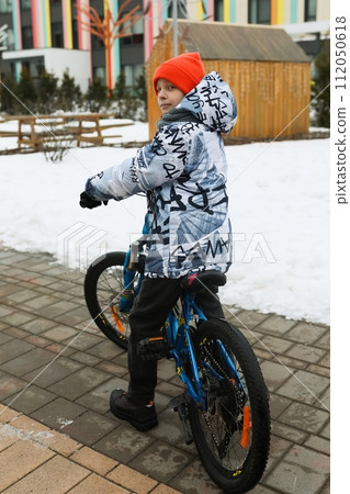 A boy in winter clothes went out for a bike ride A boy in winter clothes went out for a bike ride 112050618