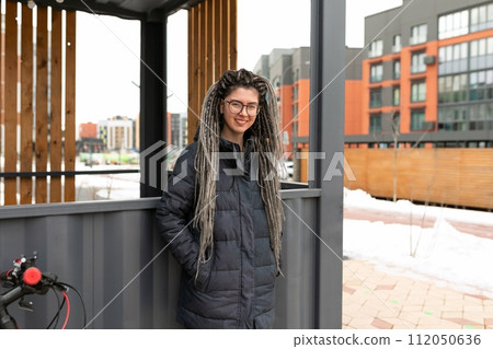 Lifestyle concept, a young pretty European woman with pigtails dressed in a warm winter jacket walks 112050636