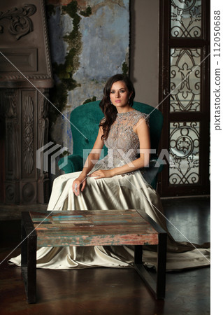 Glamorous brunette woman posing in dark vintage interior Glamorous brunette woman posing in dark vintage interior 112050688