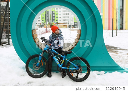 Boy in winter clothes took a break while riding a bike Boy in winter clothes took a break while riding a bike 112050945