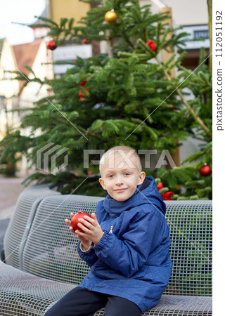 Winter Wonderland Delight: 8-Year-Old Boy with Christmas Decor by Vintage Fountain. 112051192