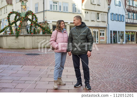 Loving couple of tourists walking around old town. Couple of lovers leisurely stroll in the cool autumn morning on the streets of a BIETIGHEIM-BISSINGEN (Germany). The guy holds his wife. Vacation 112051201