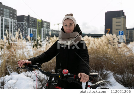 Cute young woman riding a bicycle in winter 112051206