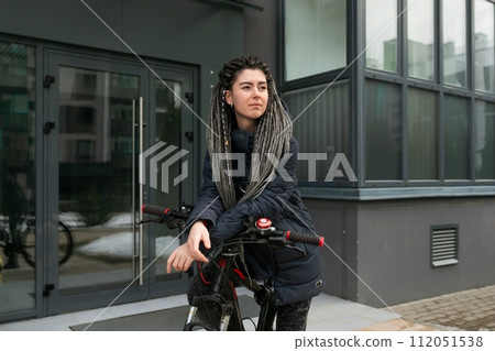 Urban pretty woman with dreadlock hairstyle rides a bicycle Urban pretty woman with dreadlock hairstyle rides a bicycle 112051538