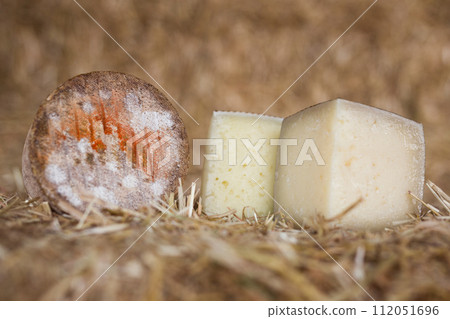 Head and chunks of aged hard cheese in hayloft Head and chunks of aged hard cheese in hayloft 112051696