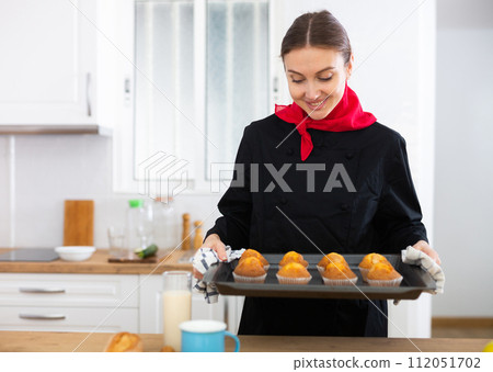 Portrait of positive female chef with just baked hot cupcakes 112051702