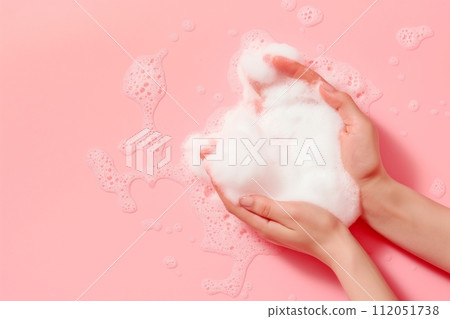 Womans hands play with sudsy soap foam on a soft pink background Womans hands play with sudsy soap foam on a soft pink background 112051738