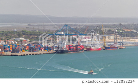 Aerial view of various containers stored in the container terminal near water timelapse, Setubal, Portugal 112052224