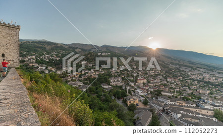 Panorama showing sunset over Gjirokastra city from the viewpoint of the fortress of the Ottoman castle of Gjirokaster timelapse. 112052273