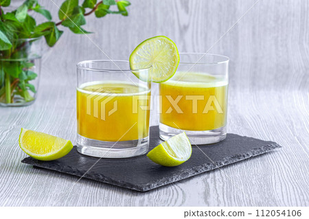 Fresh lime juice in glasses on slate coaster. World Juice Day. Fresh lime juice in glasses on slate coaster. World Juice Day. 112054106