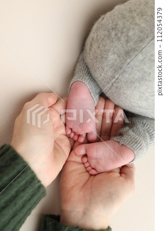 The palms of the father, the mother are holding the foot of the newborn baby. Feet of the newborn on the palms of the parents. Studio macro photo of child's toes, heels and feet on a white background. The palms of the father, the mother are holding the foot of the newborn baby. Feet of the newborn on the palms of the parents. Studio macro photo of child's toes, heels and feet on a white background. 112054379