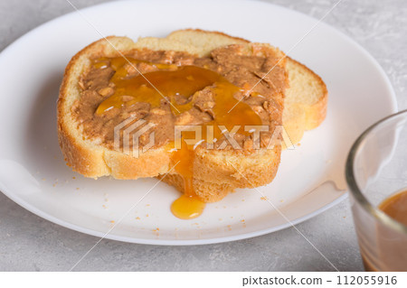 Sandwich with honey and peanut butter spreading on piece of white bread toast, close up Sandwich with honey and peanut butter spreading on piece of white bread toast, close up 112055916