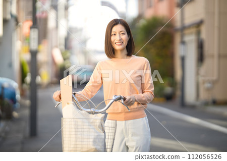 Middle-aged woman going shopping by bicycle Middle-aged woman going shopping by bicycle 112056526