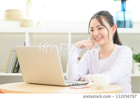 A woman looking at a computer while taking notes 112056787