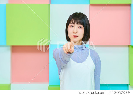 Colorful background with young woman in pointing pose 112057029