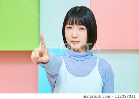 Colorful background with young woman in pointing pose 112057031