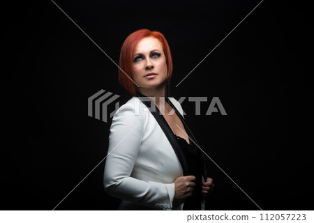 attractive woman in a white suit jacket on dark background and soft lighting as an advertising model attractive woman in a white suit jacket on dark background and soft lighting as an advertising model 112057223