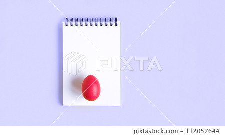 Notebook with red Easter Egg. Spiral notepad on spring violet background. Top view of open writing pad with blank page, office flat lay. White Page for your write. Copy Space. Easter Mock Up Notebook with red Easter Egg. Spiral notepad on spring violet background. Top view of open writing pad with blank page, office flat lay. White Page for your write. Copy Space. Easter Mock Up 112057644