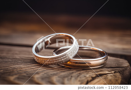 Two wedding rings jewelry lying on a rustic wooden surface 112058423