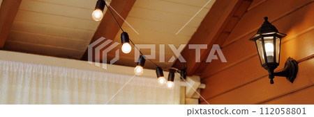 Banner Illuminated string lights on a wooden patio. Banner Illuminated string lights on a wooden patio. 112058801