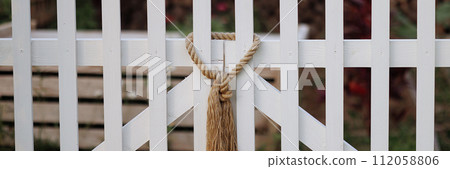 Banner rope knot on white picket fence. 112058806