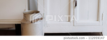 Banner vintage milk can on woven rug, rustic interior. Banner vintage milk can on woven rug, rustic interior. 112059147