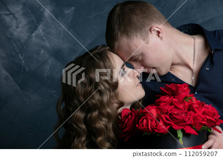 Beautiful young couple .Hugs, kisses and enjoys spending time together, celebrating Valentines Day with red roses. Beautiful young couple .Hugs, kisses and enjoys spending time together, celebrating Valentines Day with red roses. 112059207