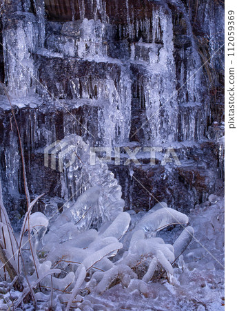 Frozen ice cycles hanging from rocks. 112059369