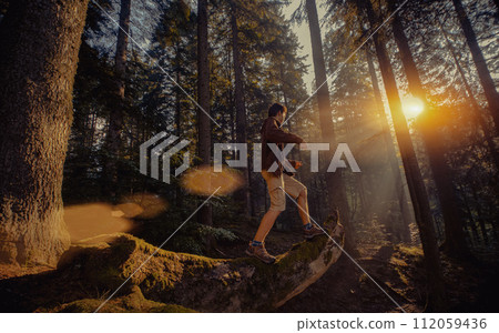 Man trekking in woods in bright sunlight 112059436