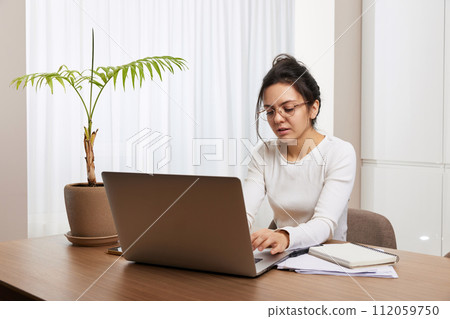 pretty woman in glasses using laptop and communicates with customer on internet at home 112059750