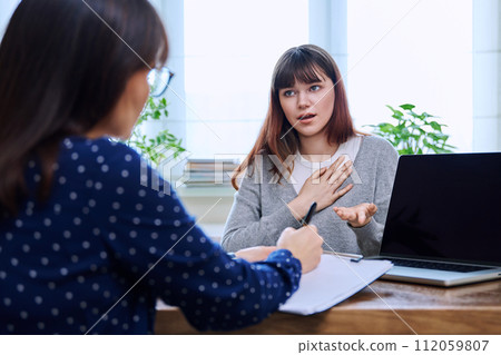 Sad, serious teenage girl at session in office of mental professional 112059807