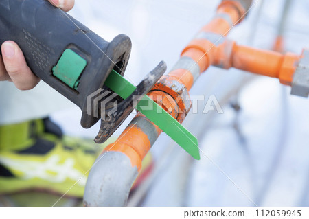 Workers at hand removing existing pipes 112059945