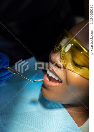 Woman in protective glasses visiting dentistry clinic for teeth treatment 112060082