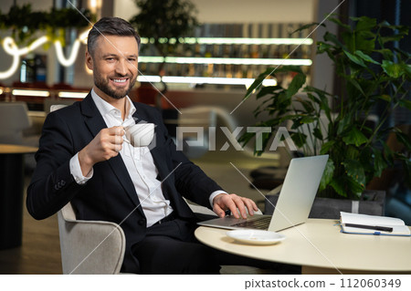 Young elegant businessman working in the office and having coffee Young elegant businessman working in the office and having coffee 112060349