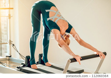 Active woman using Pilates equipment to improve her physical flexibility 112060364