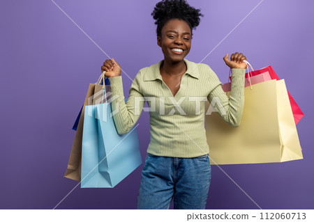 Smiling pretty dark-skinned girl with gift bags looking excited 112060713